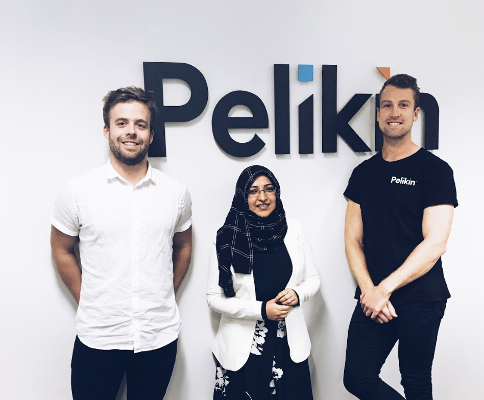 A female international student wearing hijab standing with two male internship host company mentors