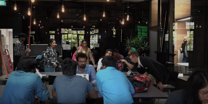 Teams of international students sitting at desks discussing industry projects