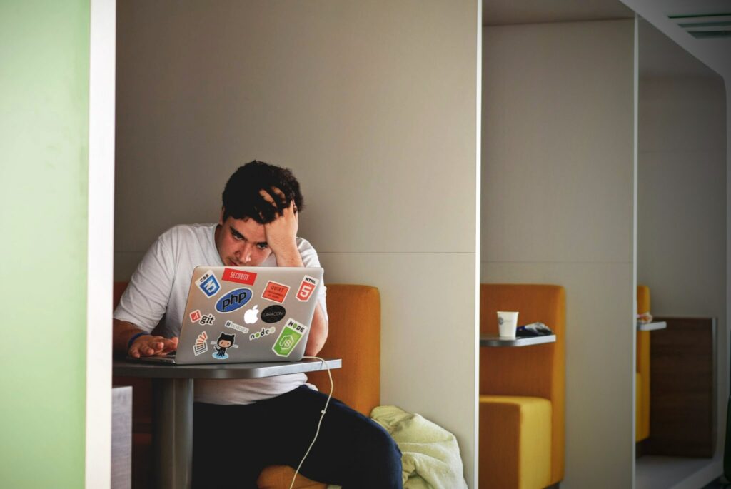 Stressed student stares at his laptop in a co-working space.