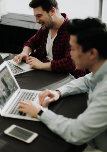 Two students on their laptops in a co-working space. Two students on their laptops in a co-working space.